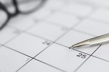 Silver pen lying at blank paper timetable