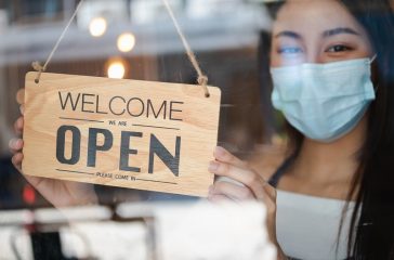 Owner retail,coffee shop woman turning sign board to open with wearing face mask ,protection to pandemic of coronavirus reopen store,restaurant after close lockdown quarantine in covid to new normal.