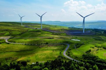 Aerial view of large wind turbines on a rural hillside in Wales