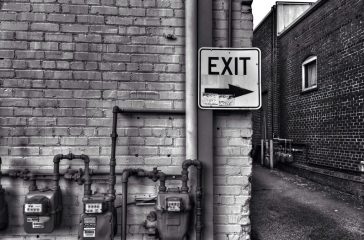 Close-up Of Exit Sign On Brick Wall