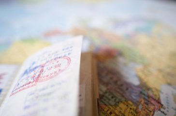 (Selective focus) A passport with entry stamps is on a blurred geographical map of the world.
