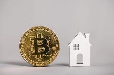 Gold bitcoin coin, model house on a gray background. property. Copy space. Color of the year 2021 illuminating and ultimate gray pantone.
