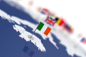 Ireland flag in the focus. Europe map with countries flags