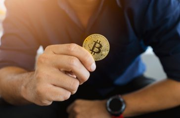 golden bitcoin in a businessman hand in the office with soft foc
